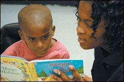 Urban Teacher Academy Program trainee Elizabeth Noel, who's also a student at Stranahan High, reads to first grader Rayon James.
