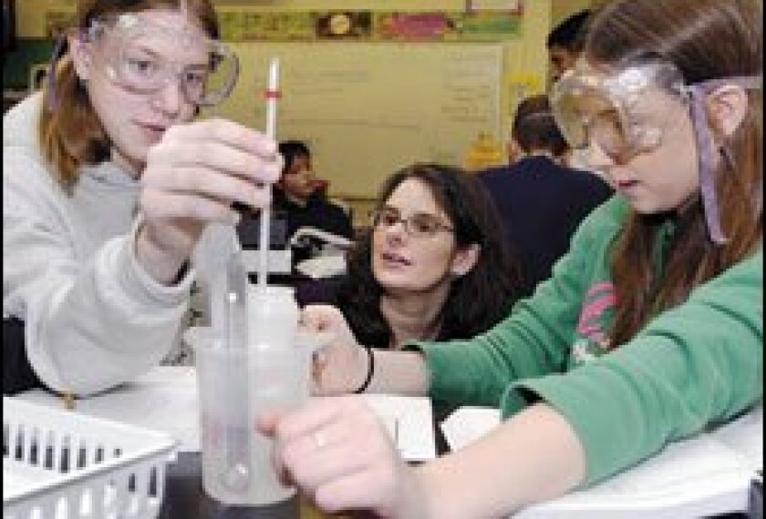 Melissa Jaeger, center, an 8th grade science teacher at Lakeshore Middle School in Grand Heaven, Mich., helps Emily Thomas, left, and Sara Sturgill perform a heat conduction experiment. Schools are gearing up for federal science-testing requirements.
