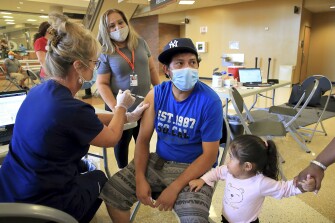 RN Dianne Moellering, left, gives Jose Luis Villanueva Hernandez his first dose of the Pfizer COVID-19 vaccine as his daughter Natalie, 2, watches during a vaccination clinic at Ritenour High School on Wednesday, Aug. 11, 2021, in St. Louis County, Mo. "I didn't feel nothing" said Hernandez. The vaccinations were available to anyone in the community.