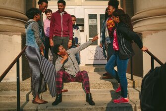 Lindblom Math & Science Academy senior Ebere Forbes-Wilson, 18, in gray, jokes with classmates on the Chicago school campus. The students recently wrote a song in response to the district’s budget crisis and performed it at a school board meeting. Choir teacher Casey Fuess is in back.