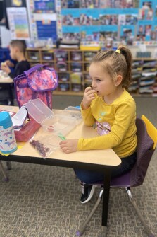 Kindergartner Riley McFerron eats lunch in her classroom at Quincy Elementary School in Zeeland, Mich. The school also shortened lunch and extended recess, minimizing the amount of time that students spend indoors maskless.