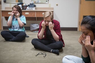 From left, students Shantell, 18, Lacey, 16, and Luxxus, 16, follow along during a guided tapping class, a form of guided mindfulness, at a dorm at the Wyoming Girls School. Afternoons and evenings are dedicated to various individual and joint counseling groups, occupational therapy, and other activities. Dixie Cooper, the principal at the Wyoming Girls School, notes: “We have about 25 percent with an active IEP–but almost any of the kids would qualify” for an individualized education plan, based on learning disabilities, emotional disturbances, or both. Only a student’s home school can start a new IEP, and while the Girls School can suggest additions to a student’s IEP, discussions about how a 16-year-old ended up reading at a 1st grade level can get diplomatically tricky.