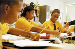Precious Pearson, 15, center, helps Tiffany Gilliam, 16, with an assignment as Devon Little, 14, looks on during a class at the Talent Development High School in Baltimore.