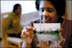 Schondra Sweeney holds a photo of the street in Waveland, Miss., where their storm-damaged home still stands.