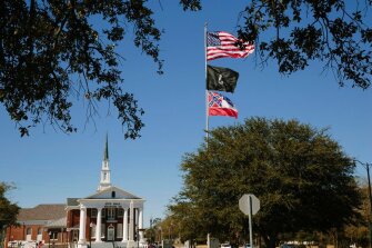 The Mississippi state flag flies beneath a POW/MIA flag and the American flag in front of City Hall in Picayune, Miss.