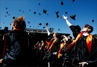 Damian Ferguson, right, celebrates with classmates at the conclusion of the commencement ceremony for the Roseburg High School graduating class of 2014 at Finlay Field in Roseburg, Ore.