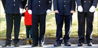A child peers through firefighters standing at attention as a procession heads to the cemetery outside the funeral for school shooting victim Daniel Gerard Barden in Newtown, Conn. According to firefighters, Daniel wanted to be a firefighter when he grew up and they honored him at the service.