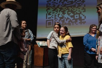 Danaé Tinajero, who finished second, hugs winner Melody Hinkle after the National Spanish Spelling Bee at the National Hispanic Cultural Center on July 12, 2025.