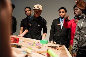 Tenth grader Daryus Bell, center, and classmates try to maneuver a marble through a maze built as part of an engineering project.