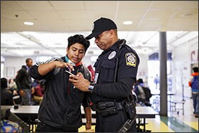 Grady High Senior Jordi Perulero, left, uses a phone to show Hammond proof that he works as a cook in one of the officer’s favorite restaurants.