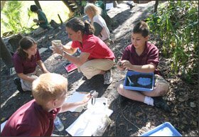 Teacher Heather Lowder, center, shows how worms and various objects are separated by a sifter during an outdoor class at the Learning Gate School.