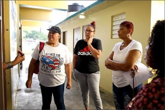 Parents listen to Principal Annette Astrid Llanos Algarin, out of frame at left, during a walkthrough at Escuela Pedro Albizu Campos in Canovanas, Puerto Rico. Some parents were alarmed that the building was still in a state of disrepair on the first day of school.