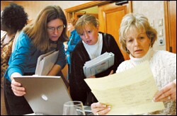 Program participants Sandra Hovis, left, Jill Gaitens, center, and Elizabeth Apolito review contact information for fellow students from around the country on their last day together in Washington after a week of classes and outings.