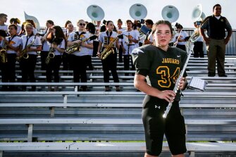 Dressed in her shoulder pads and jersey, 8th grader Julie Michael, 13, holds her flute before playing the national anthem with the marching band at Seven Springs Middle School in New Port Richey, Fla. Julie is a kicker on the football team, and also plays linebacker and wide receiver.