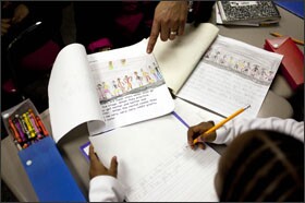 Jodi Burroughs, principal of Dr. Martin Luther King Elementary School and a trained literacy coach, works one-on-one with a 1st grader during a writing workshop. Burroughs says the Literacy Collaborative's strength is that it facilitates "embedded PD."