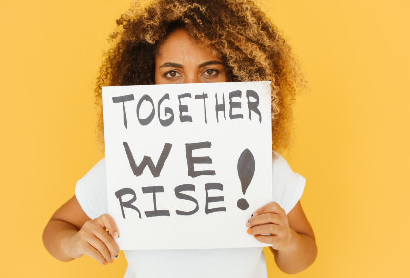 Image of woman with a "Together We Rise!" sign.
