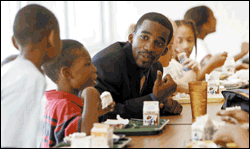 Jean, who always wears a coat and tie to work, talks to his 3rd graders at lunch.