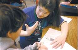 Teaching assistant Amy Liu works with Andrew Lockeharris during a Mandarin-only social studies class at Hosford Middle School. Her son Andres is also in the district's Chinese-immersion program.