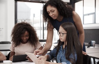 Teacher helping high school students with technology