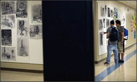 Freshman John Reverdes, left, and sophomore Daniel Jaramillo view drawings on display from their art class at Jacqueline M. Walsh School for the Performing and Visual Arts in Pawtucket, R.I. Six high schools in that state will take part in an international pilot exam focused on individual schools’ performance.
