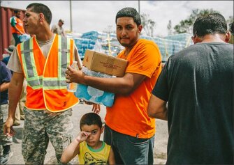 Jeremy Vasquez holds his nephew Jamdry Salsado, 2, as he waits in line for water at Ramon Luis Cabanas baseball stadium in the San Jose neighborhood of Utuado, Puerto Rico.