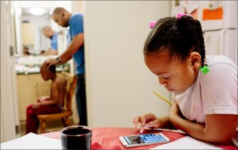 Kimora Gantt, 8, right, does homework while Jason Gantt, 5, gets his head shaved by his father, Bobby Gantt. After struggling with homelessness, the family has found stability in a home they rent through the housing authority in Tacoma, Wash.