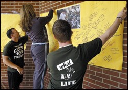 Canton High assistant football coach Howard Bell, far left, gets help hanging a poster for Gary Joe Kinne, the school's head football coach, who was hospitalized after being shot by a parent.