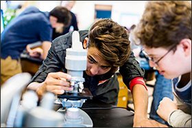 Colin Fessler, center, adjusts a microscope in his 10th grade science class at Kohler High School in the neighboring district of Kohler.