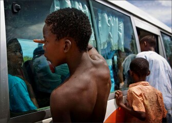 VLA student Anarree Jonson looks out the bus window as a young, Haitian boy peers in, hoping for a gift he can sell or use at the Sosua dump where he and other homeless people live and work.