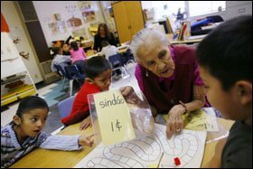 Volunteer Nellie Curley works with Sky Yazzie, 6, right, on a math game at the Navajo Language Immersion School, where children are taught in English and in Navajo.