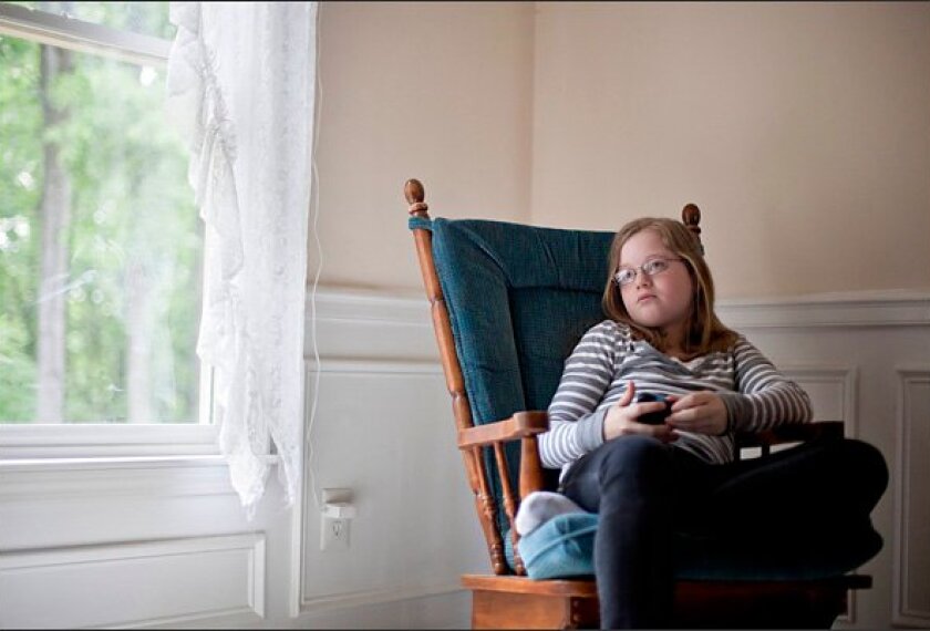 Alex Boston, 14, sits in her home in Acworth, Ga. Boston's family this month filed a libel lawsuit claiming two classmates humiliated her by using a doctored photo to set up a phony Facebook account in her name, and then stacking the page with phony comments claiming Boston was sexually active, racist, and involved in drugs.