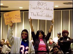 Colby McLean, left, and Keyona Turner hold signs in favor of Harbor city West High, which is slated to be closed.
