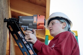 Sophomore Seairra Ferguson, 16, uses a nail gun to attach plywood sheathing on a tiny house on Friday, March 22, 2019 at Battle High School in Columbia, Mo. Students in a combined construction and geometry class are building a tiny house for a low-income family in the community.