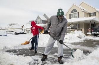 Christopher Middlebrooks and his son Mitchell Middlebrooks work to clear their driveway in the Larkin district in Buffalo, N.Y., Friday, Nov. 18, 2022.