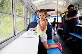 Four-year-old Racqul Rivera munches on a peanut-butter-and-jelly sandwich inside Pasco County, Fla.’s lunch bus. Children wait in line daily in the summer to board the rolling cafeteria, which was constructed from a retired school bus retrofitted with lunchroom tables.