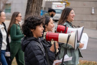 A group of youth demonstrators walking on unknown street with megaphones in hand