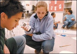 Using an iPod, 8th grader Elizabeth O'Neil records an interview with classmate Davis Tran as he works on the set design for a play at Gunston Middle School.