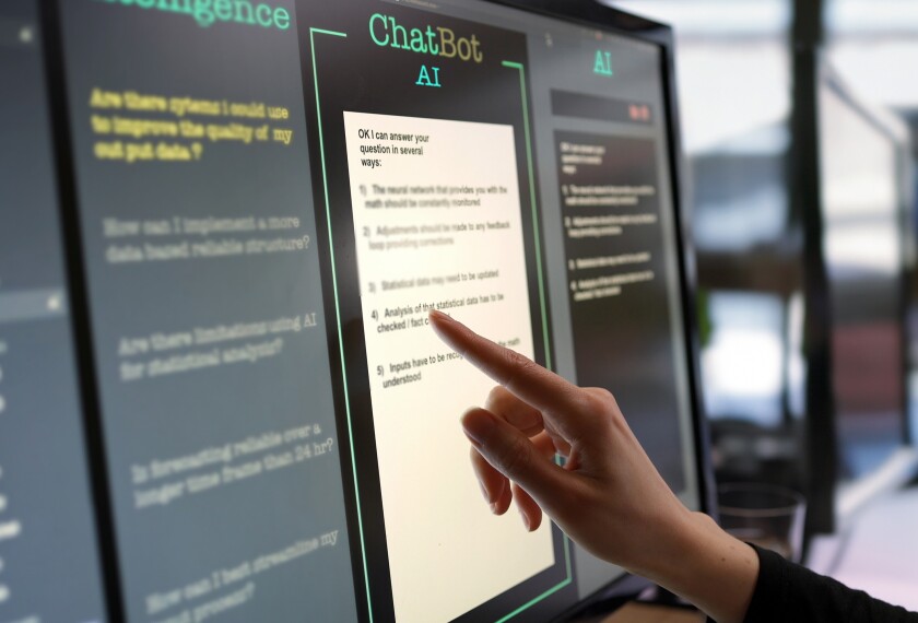 Close-up stock photograph showing a touchscreen monitor with a woman’s hand looking at responses being asked by an AI chatbot.