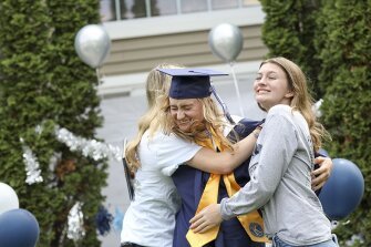 Ellie Tanko is hugged by Abby Tanko (left) and Anna Tanko, 16, after graduating during a diploma delivery to Xavier High School seniors around Cedar Rapids and Hiawatha on Wednesday, May 13, 2020. The school held a virtual prom and is holding a virtual Baccalaureate mass, in addition to the drive-by graduation.