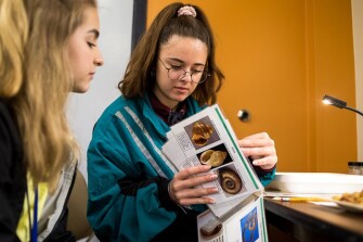 Jenna Kauffman and Jillian Chesney, seniors at Dexter High School, in Dexter, Mich., flip through a bug identification chart.