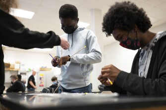 Sophomores in the aviation program at Magruder High School in Rockville, Md., work together to assemble a helicopter during class on April 7, 2022.