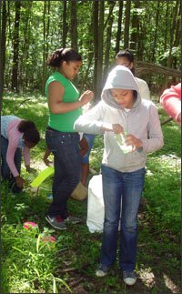 Mikiany Pena, left, and Alondra Sanchez, foreground, examine plants and animal tracks during an overnight trip to the High Bridge Empowerment Center, in Goshen, N.Y. The children in the Committee for Hispanic Children and Families after-school program are expected to take on the role of scientists.