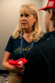 A Moms for Liberty member waits in line while clutching two ‘Make America Great Again’ hats at the annual Mom’s For Liberty Summit in Washington, D.C., on Friday, August 30, 2024.