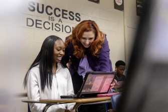 Kate Wolfe Maxlow, director of curriculum, instruction, and assessment at Hampton City Schools, reads a screenplay draft from freshman Cameron Wright, 14, during a visit to the Success 101 class at Phoebus High School in Hampton, Va., on January 12, 2024. In Success 101, freshman students are assigned to write screenplays about where they see themselves in 10 years to help them envision their post-graduation life.