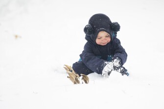 Auggie Rokitka, 2, plays in the snow with his parents, Matt Rokitka and Krissy Godios, on Richmond Avenue in Buffalo, N.Y., Saturday, Nov. 19, 2022.
