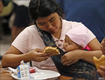Mang Don Man, of Miami, attends to her 7-month-old baby, Vung Vaang Nuam, as they eat lunch at a Red Cross shelter set up at North Miami Beach Senior High School on Sept. 8 in North Miami Beach, Fla.