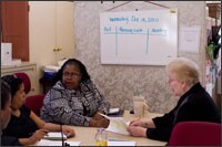 Octavia Ford, center, the on-site Children's Aid Society coordinator at PS 61, meets with Principal Pat Quigley, right social workers, and staff members. The society is working with PS 61 on its attendance push.
