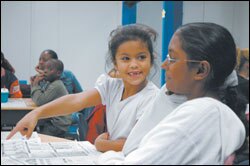 UTAP 9th grader Carmel Silviera, 14, helps 1st grader Mia Valentin, 6, with her snowflake art project.