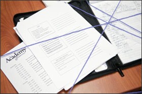 Purple yarn criss-crosses a teacher’s paperwork. As part of a training exercise, the yarn was tossed from teacher to teacher to create a web that metaphorically binds them together.