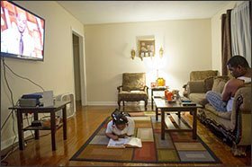 Danyelle Petty, 9, works on homework as her brother Kaylon Smith, 19, watches television at their Memphis home. Danyelle is a 4th grader at Ford Road Elementary School in Memphis, part of a 13-school “innovation zone” offering some charter-like autonomy.